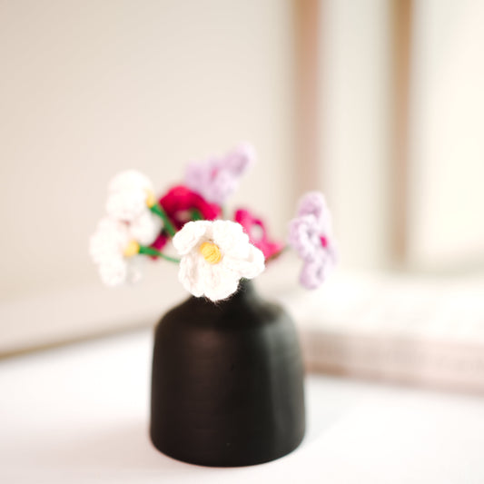 black bud vase with mini crochet daisies